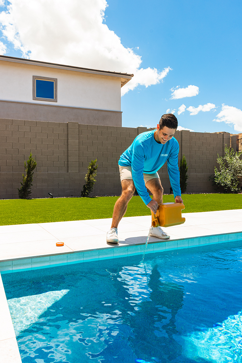 Man beside an Arizona pool pouring liquid chlorine