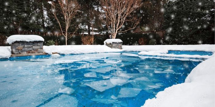 Inground swimming pool covered in snow and ice